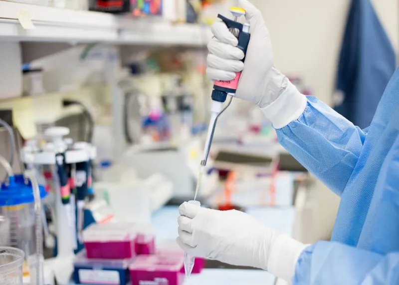 Phlebotomist drawing a blood sample from a seated patient at a collection point