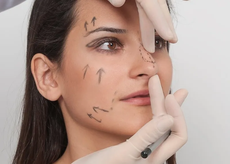 Surgeon examining a patient's face during a facelift consultation